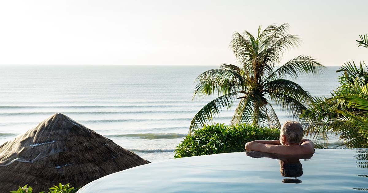 Man looking out to ocean while in infinity pool.